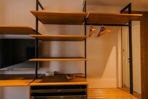 A modern room with built-in wooden shelves, a flat-screen TV, and a small kitchen area with a microwave. - Sanpietro Vacation Villa 011 (Ishëm)