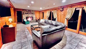 Una sala de estar acogedora con chimenea de piedra, sofá de cuero y paredes de madera.