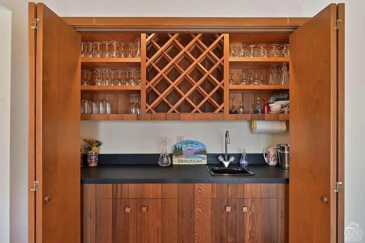 Une cuisine avec des meubles de rangement en bois, un porte-bouteilles et un panneau d’accueil.