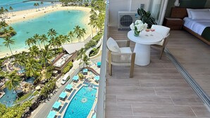 Une chambre d’hôtel avec un balcon donnant sur la plage et la piscine.