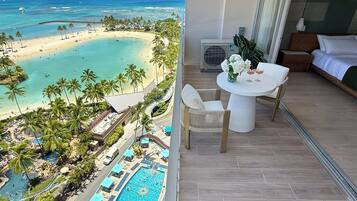 Een hotelkamer met een balkon met uitzicht op strand en zwembad.