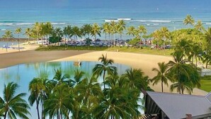 Une vue sur la plage avec un arc-en-ciel, des palmiers et une piscine.