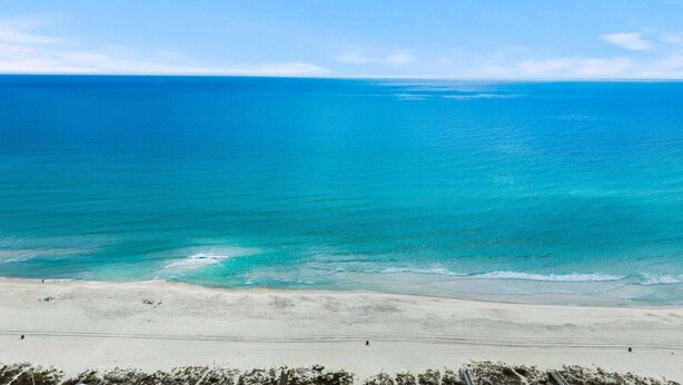 A beach with clear turquoise waters and a sandy shore.