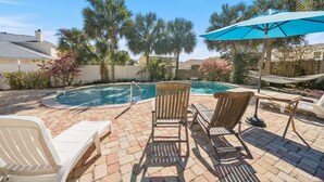 A backyard with a swimming pool, lounge chairs, and a hammock.