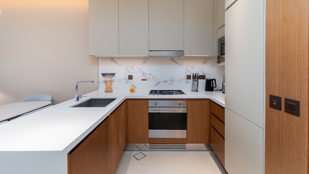 A modern kitchen with white cabinetry, a marble backsplash, and stainless steel appliances.