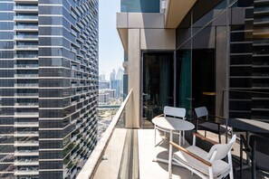 A modern building with a glass balcony, white chairs, and a table. - Address Dubai Opera 2BR | Walk to Mall, Burj Khalifa & Opera (Dubai)