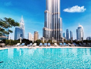 A swimming pool with lounge chairs and a city skyline in the background.