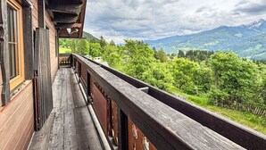 A wooden balcony with a view of a mountainous landscape.