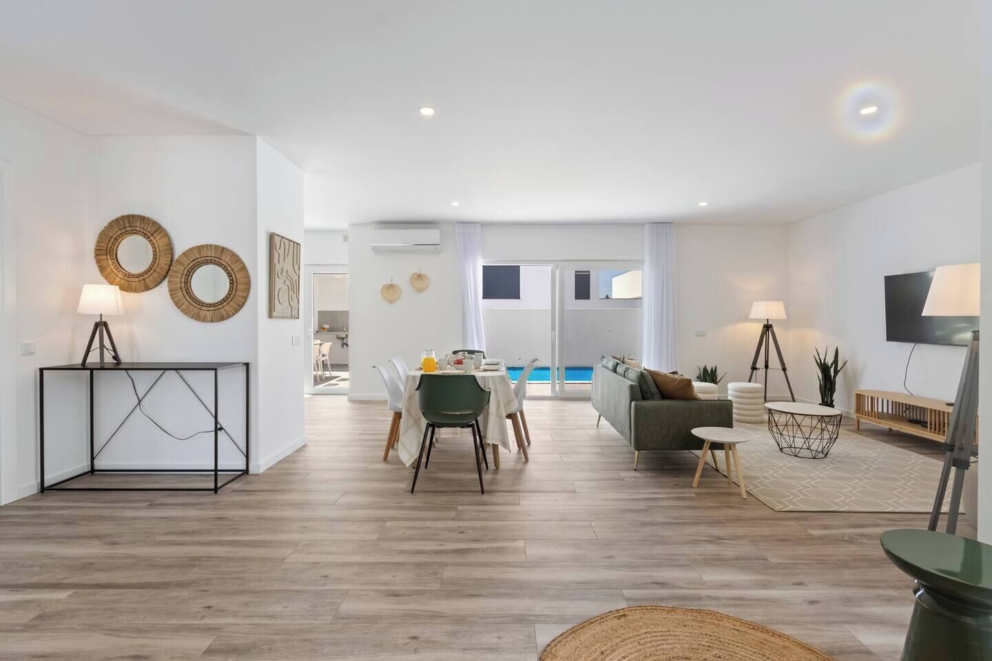 Uma sala de estar moderna com área de jantar, vista para piscina e televisão.