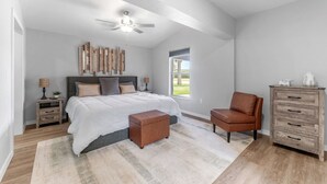 A bedroom with a large bed, a ceiling fan, a nightstand, a dresser, and a window with a view of the outdoors. - Dockside Delight! Waterfront Home + Boat Slip for Your Next Getaway (New Port Richey)