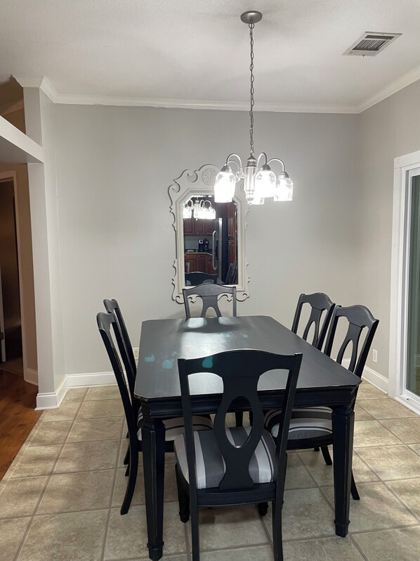 A dining room with a rectangular table, six chairs, a chandelier, and a large mirror.