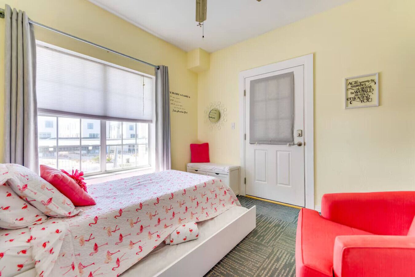Una camera da letto con un letto, una sedia rossa, una porta e una finestra.