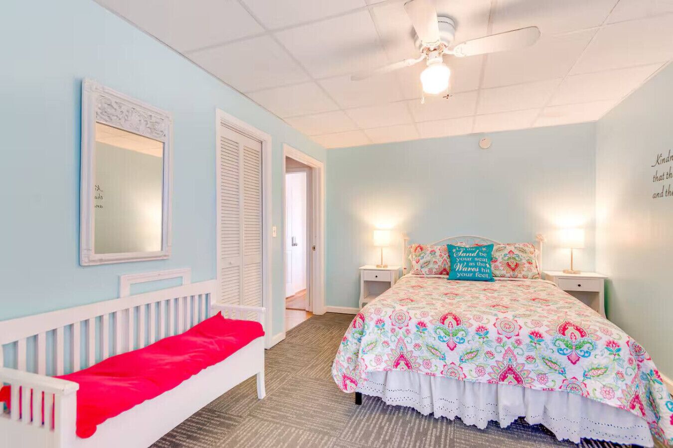 Een slaapkamer met een bed, nachtkastjes, een plafondventilator en een deur naar een andere kamer.