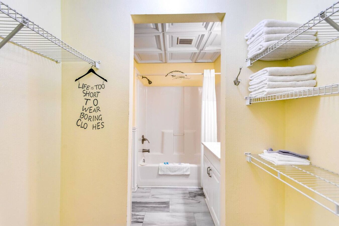 A hotel bathroom with a shower, a towel rack, and a sign on the wall.
