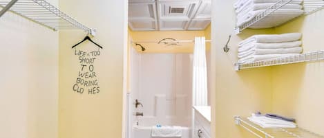 A hotel bathroom with a shower, a towel rack, and a sign on the wall.