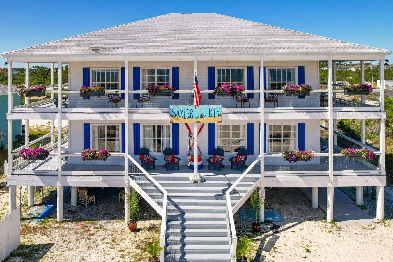 A multi-story hotel with a central staircase, balconies with flower boxes, and a sign reading "SAYLER KEY".
