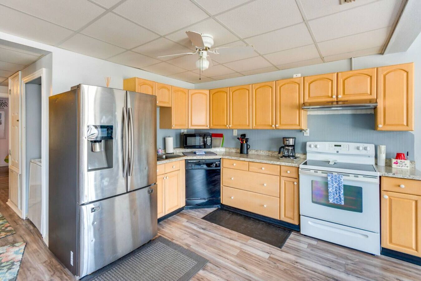 A modern kitchen with stainless steel appliances, wooden cabinets, and a tiled backsplash.