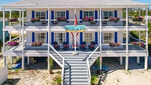 A two-story building with a covered outdoor area, multiple windows, and a flagpole with an American flag. - Deck + Gulf of America View: `Sunrise` on Perdido Key! (Pensacola)