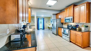 A kitchen with wooden cabinets, a stainless steel refrigerator, a microwave, and a stove.