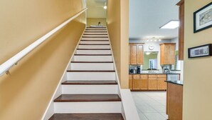 A staircase leading to a kitchen area with wooden cabinets and a tiled floor.