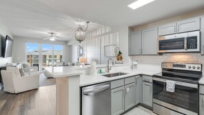 Una cocina moderna con electrodomésticos de acero inoxidable, una isla central y un comedor con sofá blanco.