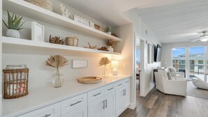 Un salón moderno con muebles blancos, un sofá blanco y vista al océano.