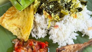 A plate of food with rice, green beans, a fried fish, and a red sauce.
