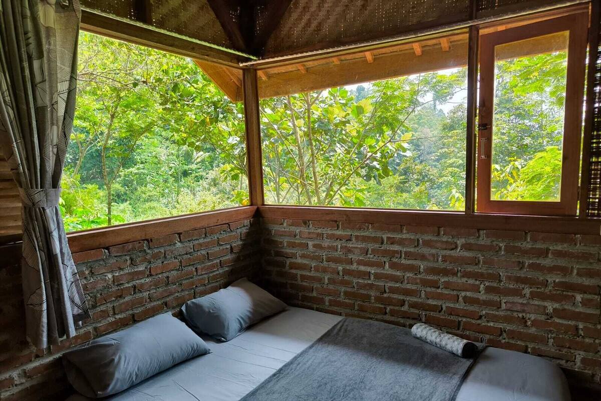 Une chambre avec un lit, une fenêtre et une vue sur la verdure.