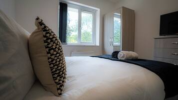 Ein Schlafzimmer mit einem großen Bett, einem Fenster, einem Kleiderschrank und einem Fernseher.