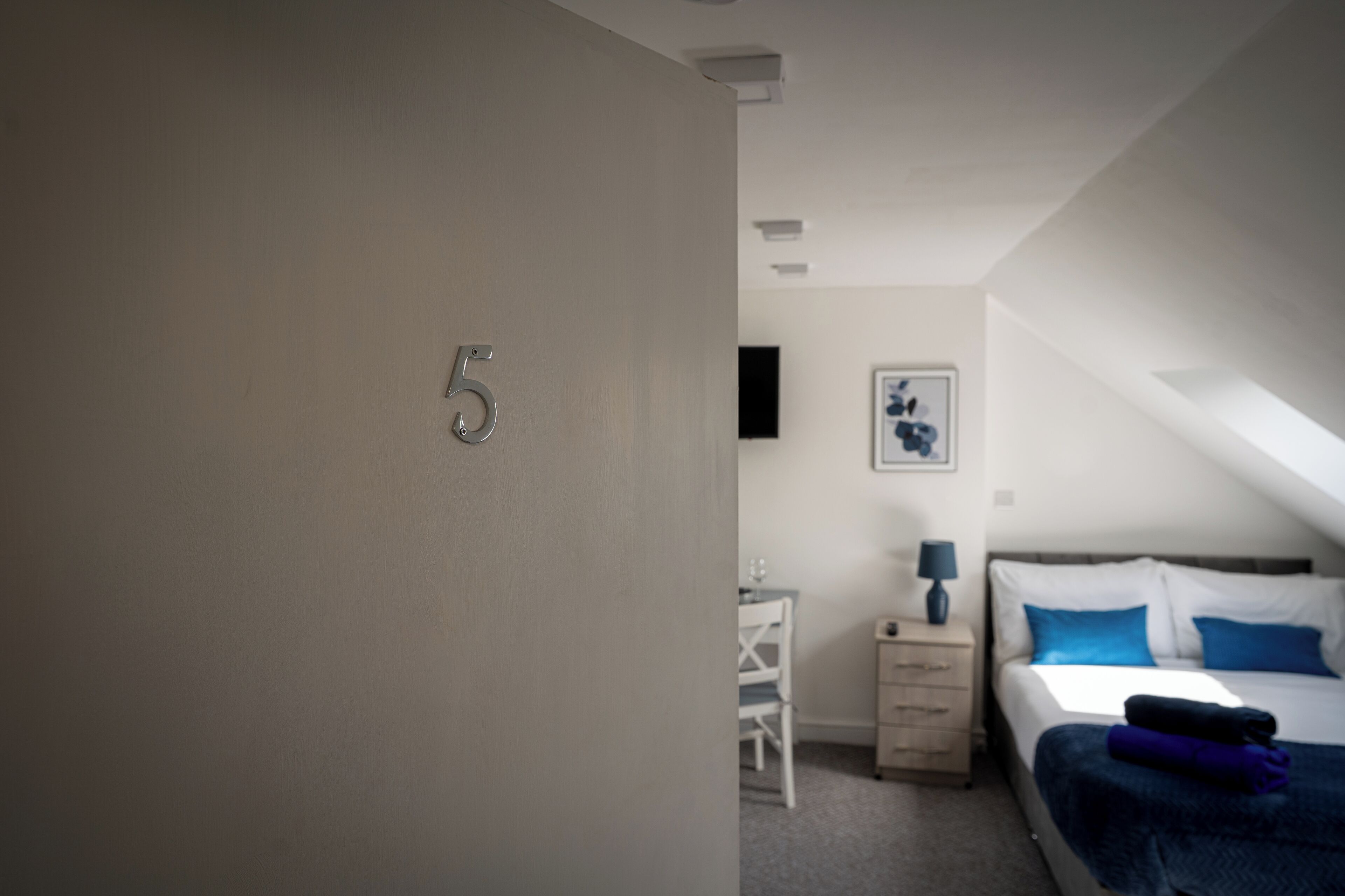 A bedroom with a bed, a desk, and a chair.