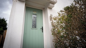 A green door with the number 59, a small window above it, and a white wall. - Beckbury House (Birmingham)