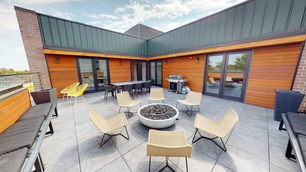 An outdoor patio with a fire pit, seating, and a grill area.