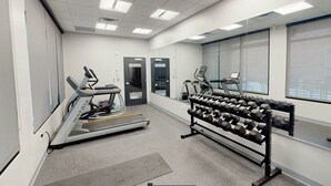 A gym with a treadmill, elliptical, and a rack of dumbbells.