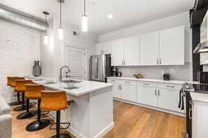 A modern kitchen with white cabinets, stainless steel appliances, and a central island with bar stools.