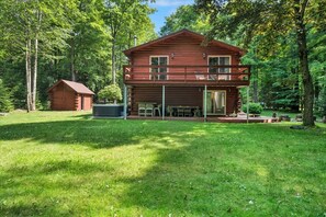 A two-story log cabin with a balcony, surrounded by a lush green forest. - Ski Chalet. EV Charger Sauna,Hot Tub,Movie Room & Firepit. PET Friendly (Blakeslee)