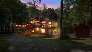 A two-story cabin with a covered deck and a staircase leading to the upper level.