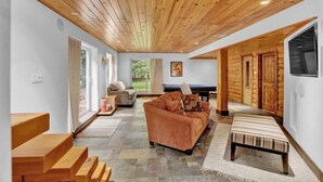 A modern interior with a wooden ceiling, a sofa, a bench, and a stone floor.