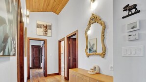 A hallway with wooden flooring, a wooden cabinet, and a large ornate mirror on the wall.