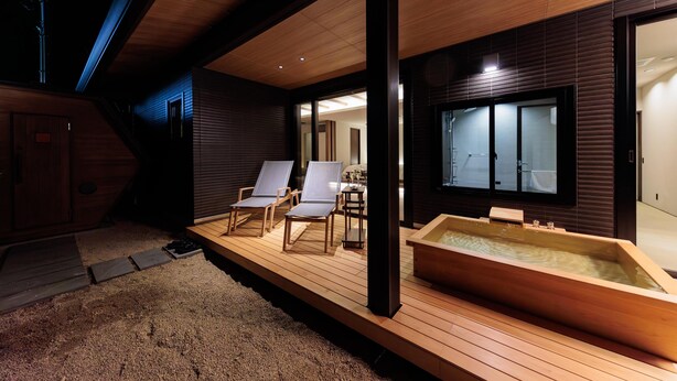 A wooden deck with a hot tub, two lounge chairs, and a view of a traditional Japanese room. - Kaigyokutei-Megumi- (Sakaiminato)