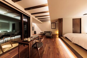 A modern hotel room with a wooden floor, a dining area with a table and chairs, a sofa, and a bed. - Kaigyokutei-Megumi- (Sakaiminato)