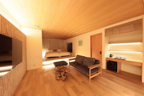 A modern living room with a wooden floor, a glass coffee table, a sofa, a TV, and a desk with a computer. - Kaigyokutei-Megumi- (Sakaiminato)