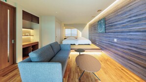 A modern hotel room with a sofa, a small round table, a bed with white bedding, and a textured wall. - Kaigyokutei-Megumi- (Sakaiminato)