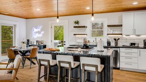A modern kitchen with white cabinets, a central island, and pendant lighting.