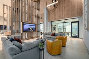 Relax in a stylish living space with a large flat-screen TV, comfortable sofa, and vibrant ottomans.