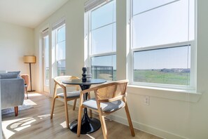 Relax in this stylish room with a round table, woven chairs, and a comfortable sofa, offering a serene view of the surrounding landscape.