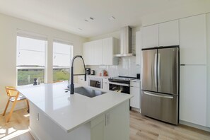 Enjoy cooking in this well-lit kitchen with a large refrigerator, oven, and central island for extra workspace.