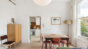 A modern apartment with a dining area, kitchen, and a large window. - GuestReady - Stylish & Spacious 1bed in Islington (London)