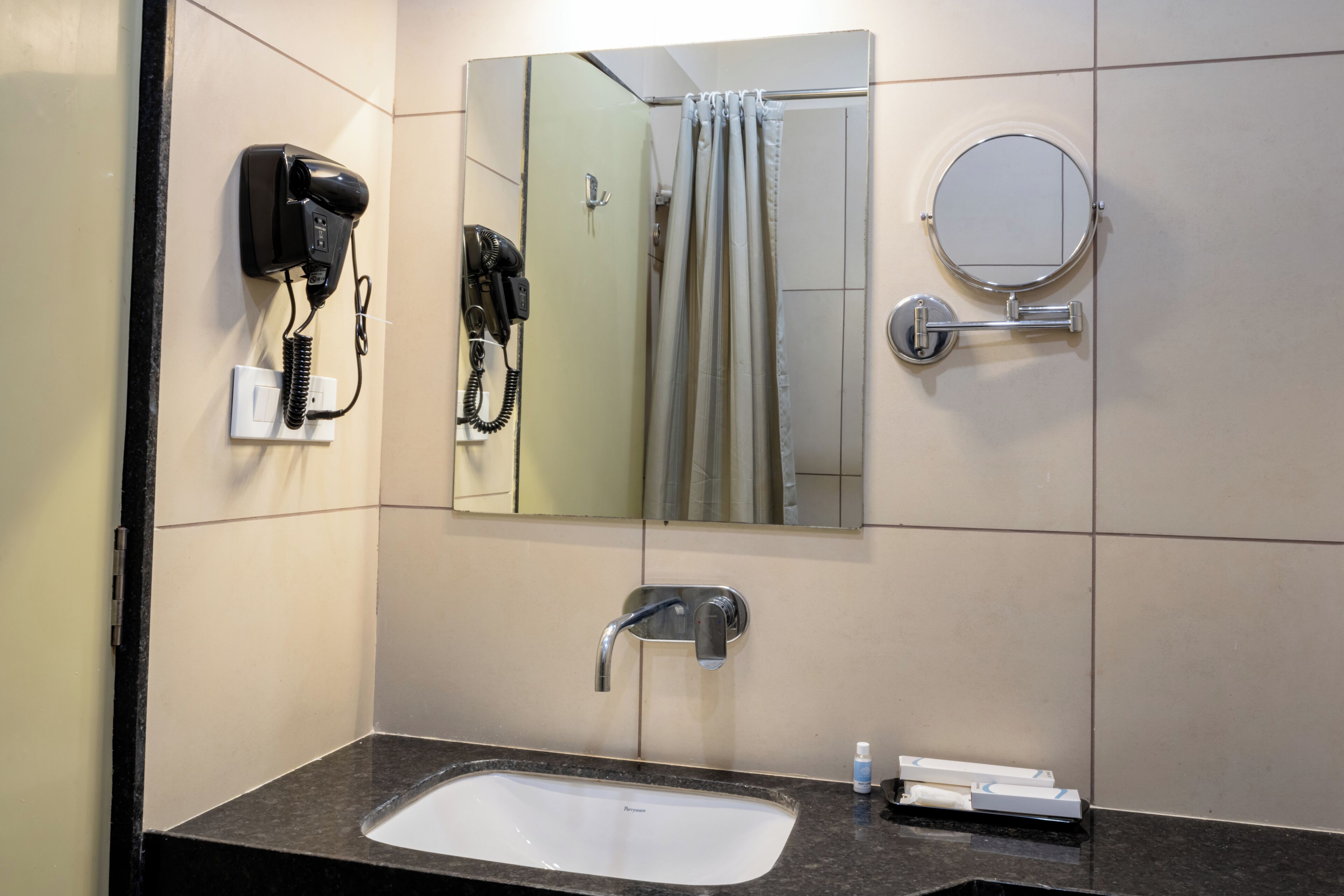 Een badkamer met een wastafel, spiegel, haardroger en handdoekhouder.