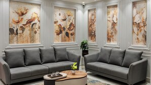 A modern living room with two grey sofas, a wooden coffee table, and large floral artwork on the walls. - Prarambh By Siara (Nadiad)