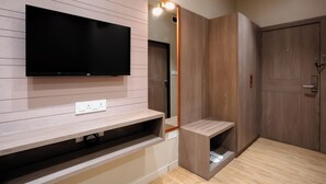 A modern room with a mounted TV, built-in shelves, a mirror, and wooden wardrobes. - Prarambh By Siara (Nadiad)